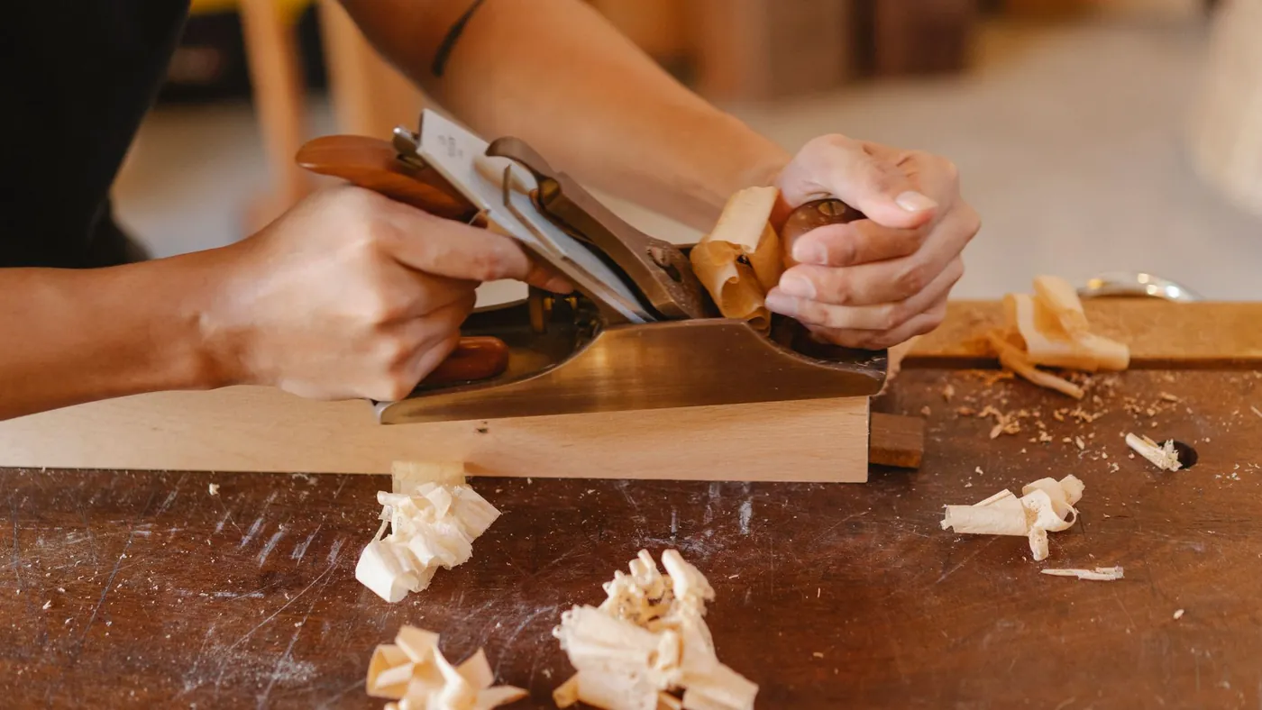 Joiner planing a wooden plank with a hand tool